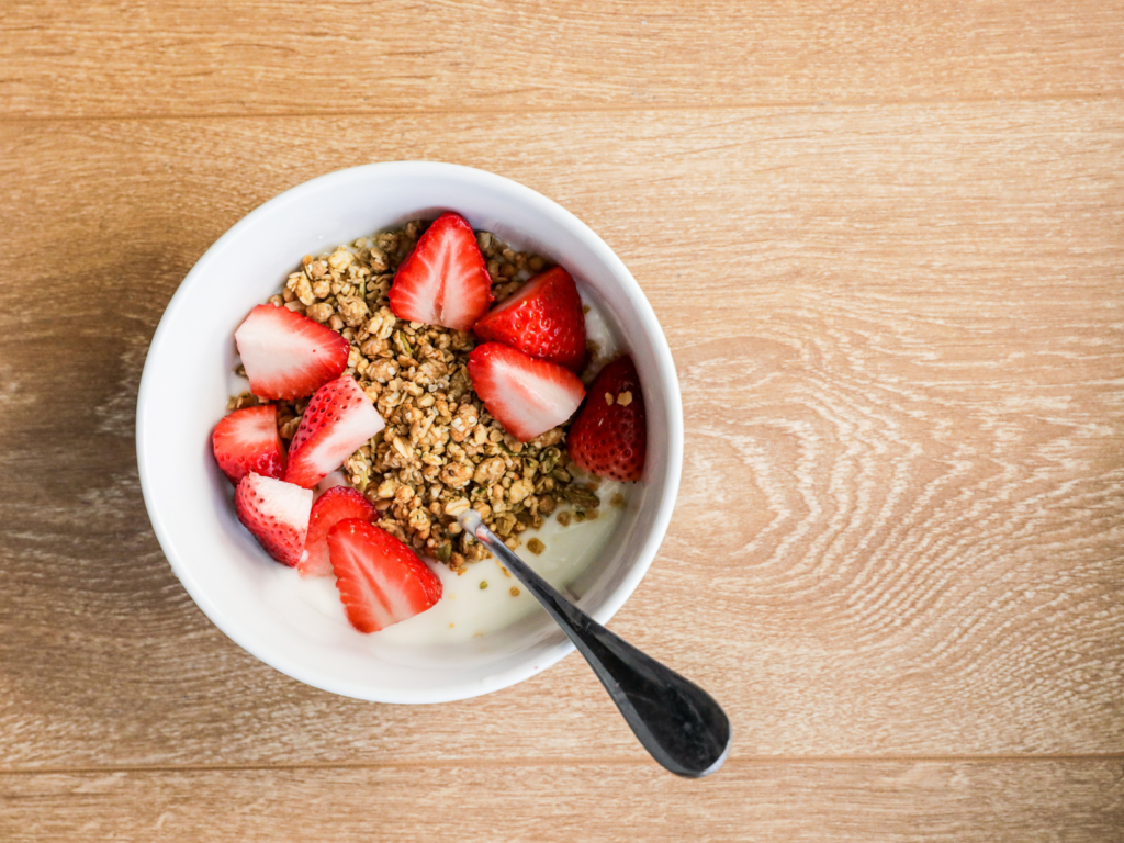 A refreshing yogurt bowl topped with fresh strawberries and crunchy granola, drizzled with honey for a perfect balance of flavor and texture.