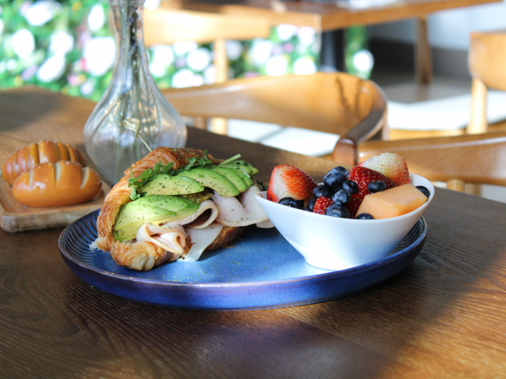 A buttery, flaky croissant filled with sliced turkey and creamy avocado, served fresh for a perfect savory bite.