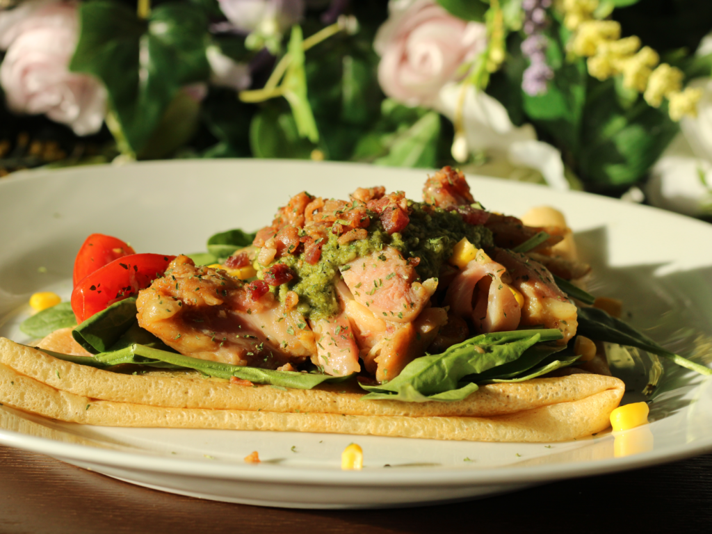 A savory pesto chicken crepe filled with tender chicken, creamy pesto sauce, and melted cheese, folded to perfection and garnished with fresh basil.