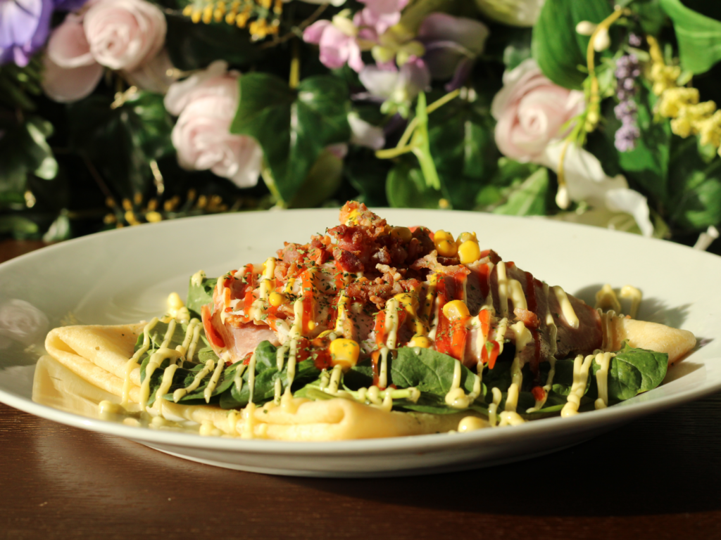A warm, savory crepe filled with melted cheese and thinly sliced ham, folded to perfection and served golden brown.