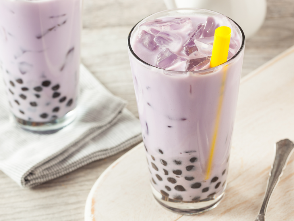 A refreshing cup of taro milk tea with creamy purple hues, served with chewy tapioca pearls in a clear glass cup.